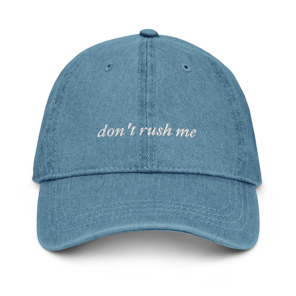 Blue denim baseball hat with 'don't rush me' text embroidered in white on a white background