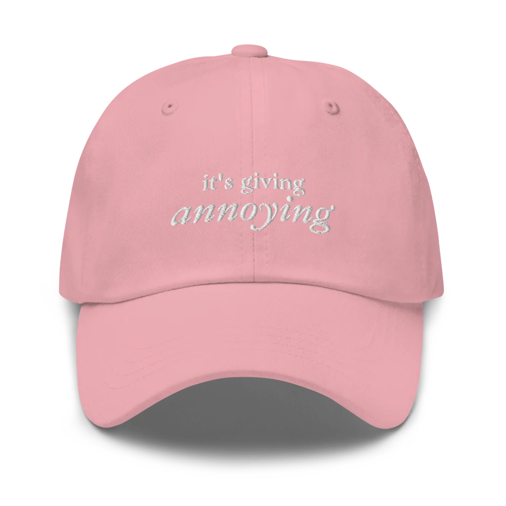 pink baseball hat with white text 'it's giving annoying' embroidered on front
