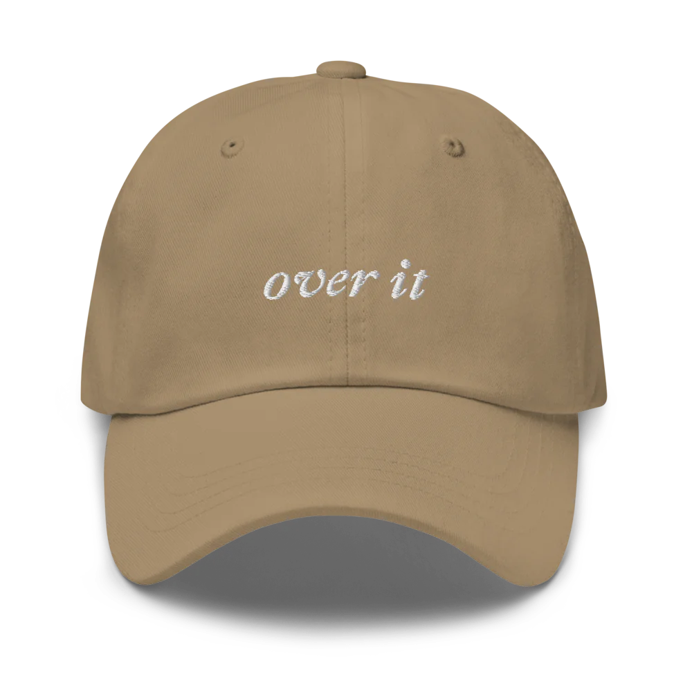 khaki baseball hat with 'over it' text embroidered in white on a white background