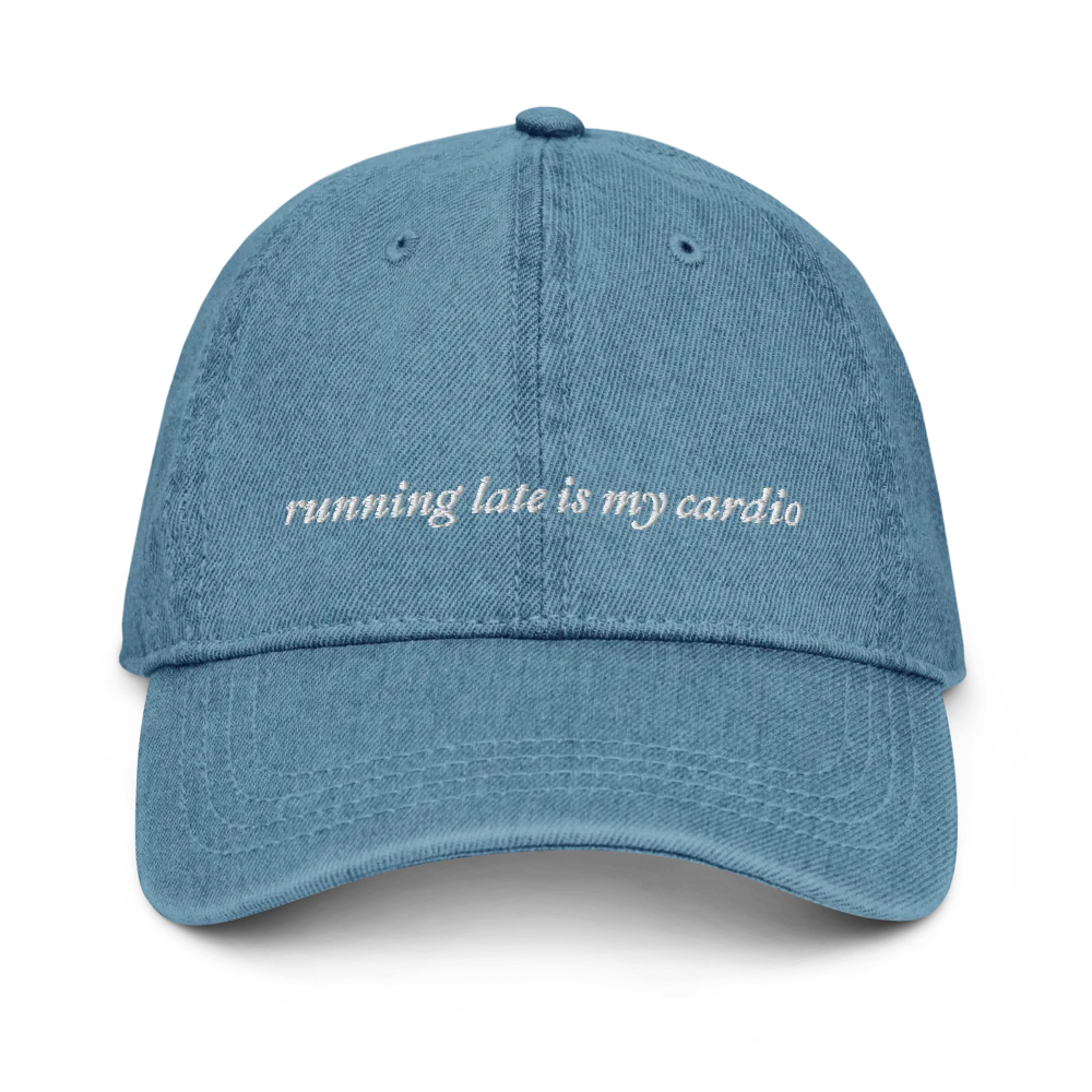 denim baseball hat with white embroidered text 'running late is my cardio' on a white background