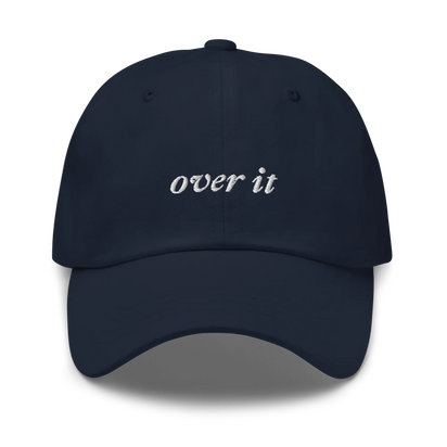 Navy blue baseball hat with 'over it' text embroidered in white on a white background