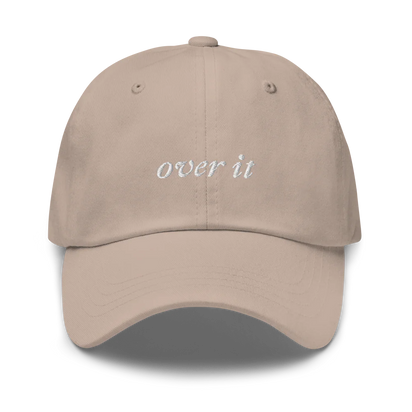 beige baseball hat with 'over it' text embroidered in white on a white background
