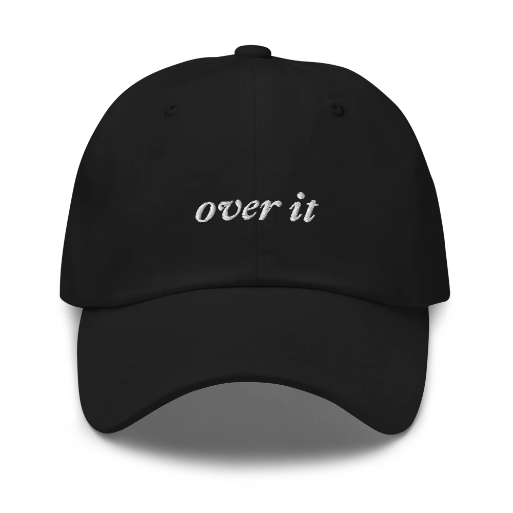 black baseball hat with 'over it' text embroidered in white on a white background