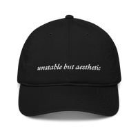 Black baseball hat with 'unstable but aesthetic' text embroidered in white on a white background