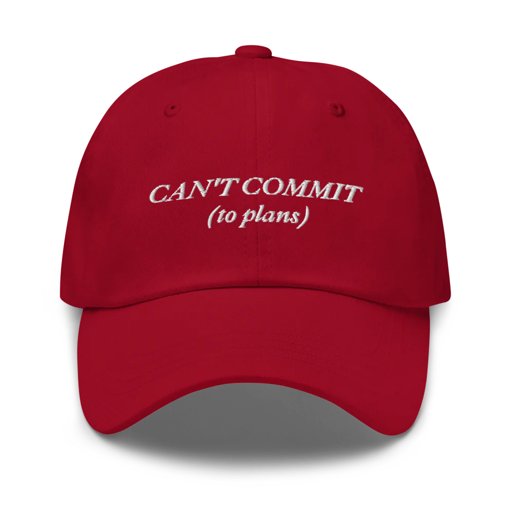 red cap with text 'CAN'T COMMIT (to plans)' embroidered in white on a white background