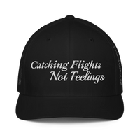 Black trucker hat with 'Catching Flights Not Feelings' text embroideredin white  on a white background