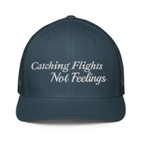 blue trucker hat with 'Catching Flights Not Feelings' text embroideredin white  on a white background