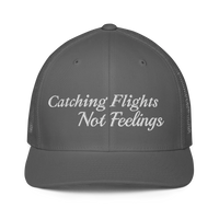 gray trucker hat with 'Catching Flights Not Feelings' text embroideredin white  on a white background