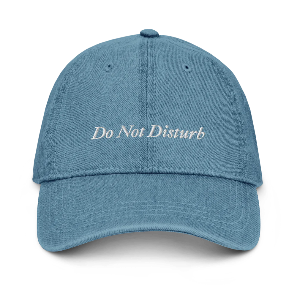 denim baseball hat with 'Do Not Disturb' text embroidered in white on a white background