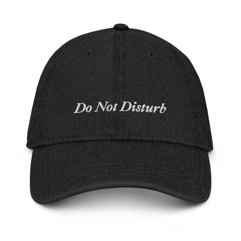 Black denim baseball hat with 'Do Not Disturb' text embroidered in white on a white background