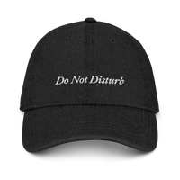 Black denim baseball hat with 'Do Not Disturb' text embroidered in white on a white background