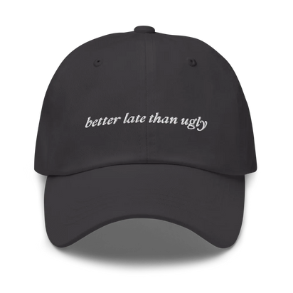 gray baseball hat with 'better late than ugly' text embroidered in white on a white background