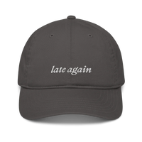 Gray baseball hat with 'late again' text embroidered in white on a white background