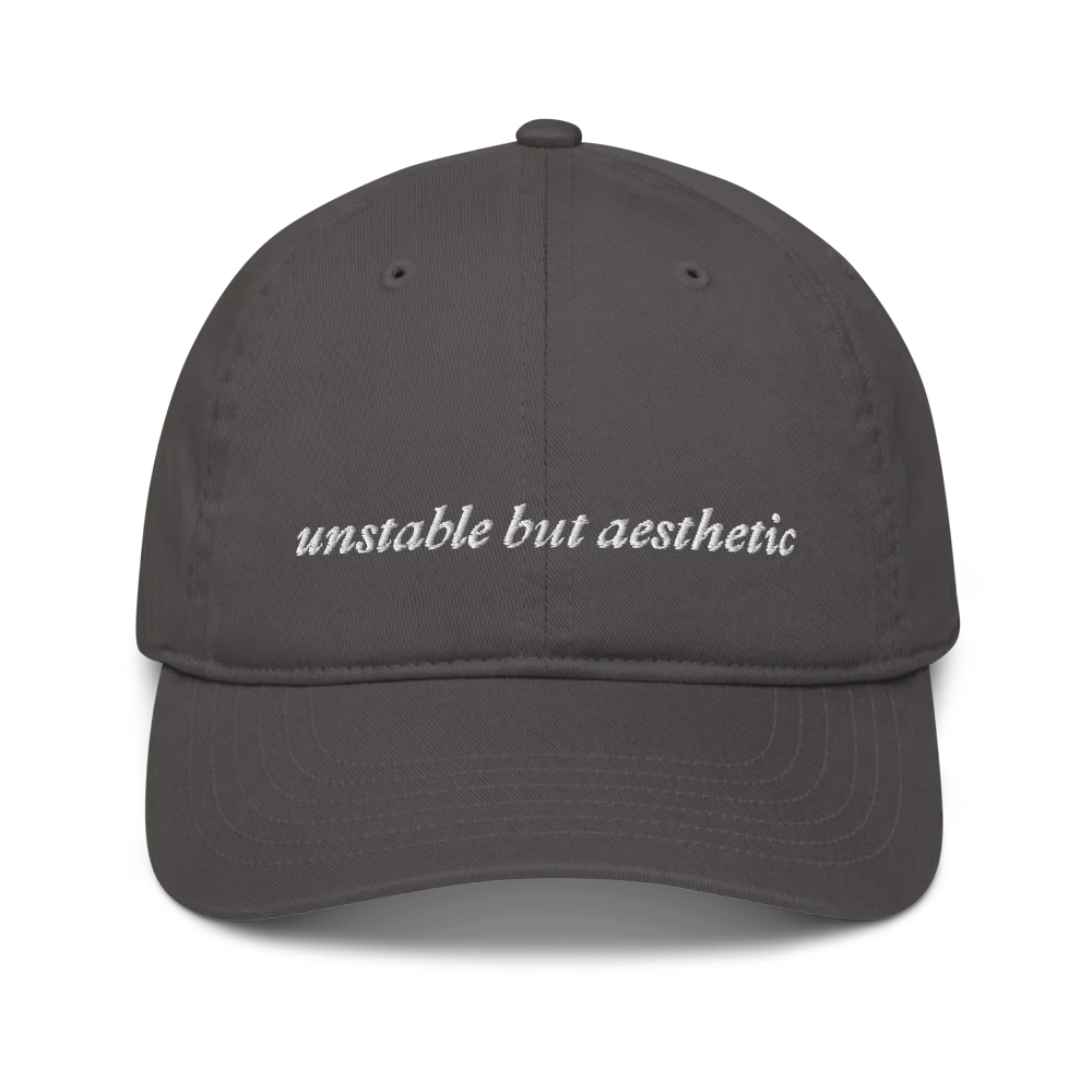 Gray baseball hat with 'unstable but aesthetic' text embroidered in white on a white background
