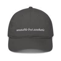 Gray baseball hat with 'unstable but aesthetic' text embroidered in white on a white background