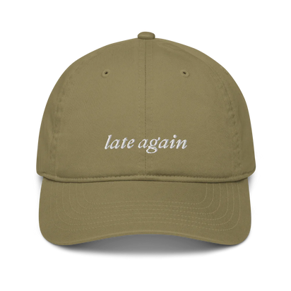 green baseball hat with 'late again' text embroidered in white on a white background