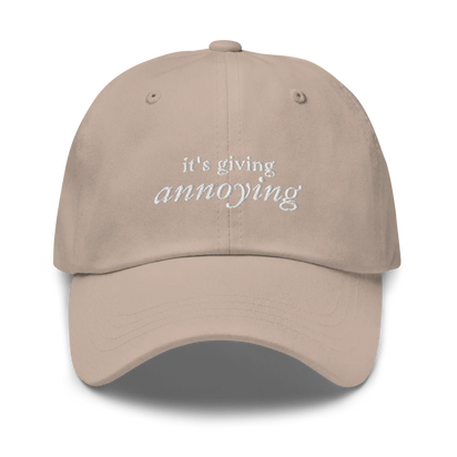 Beige baseball hat with white text 'it's giving annoying' embroidered on front