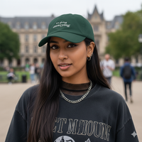 girl wearing a Green baseball hat with white text 'it's giving annoying' embroidered on front