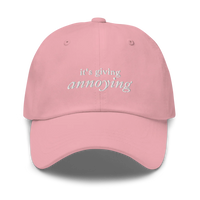 pink baseball hat with white text 'it's giving annoying' embroidered on front