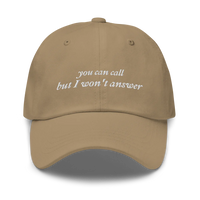 Khaki baseball hat with white embroidered text 'you can call but I won't answer' on a white background