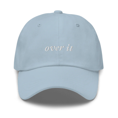 Light blue baseball hat with 'over it' text embroidered in white on a white background