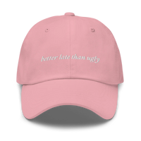 pink baseball hat with 'better late than ugly' text embroidered in white on a white background