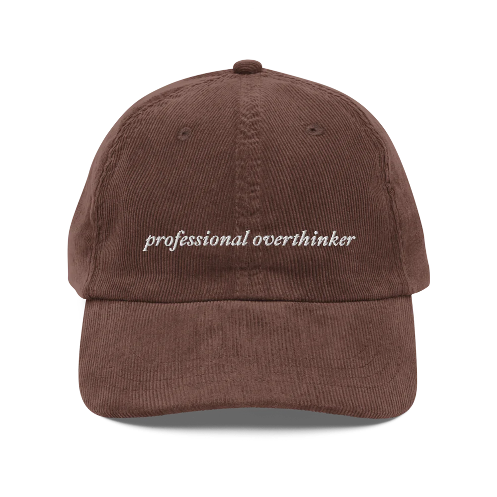 Brown corduroy baseball hat with 'professional overthinker' text embroidered in white on a white background