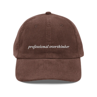 Brown corduroy baseball hat with 'professional overthinker' text embroidered in white on a white background
