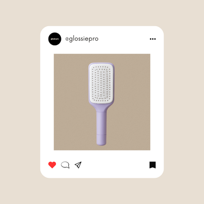 Purple self cleaning paddle hairbrush on a beige background with GlossiePro branding.