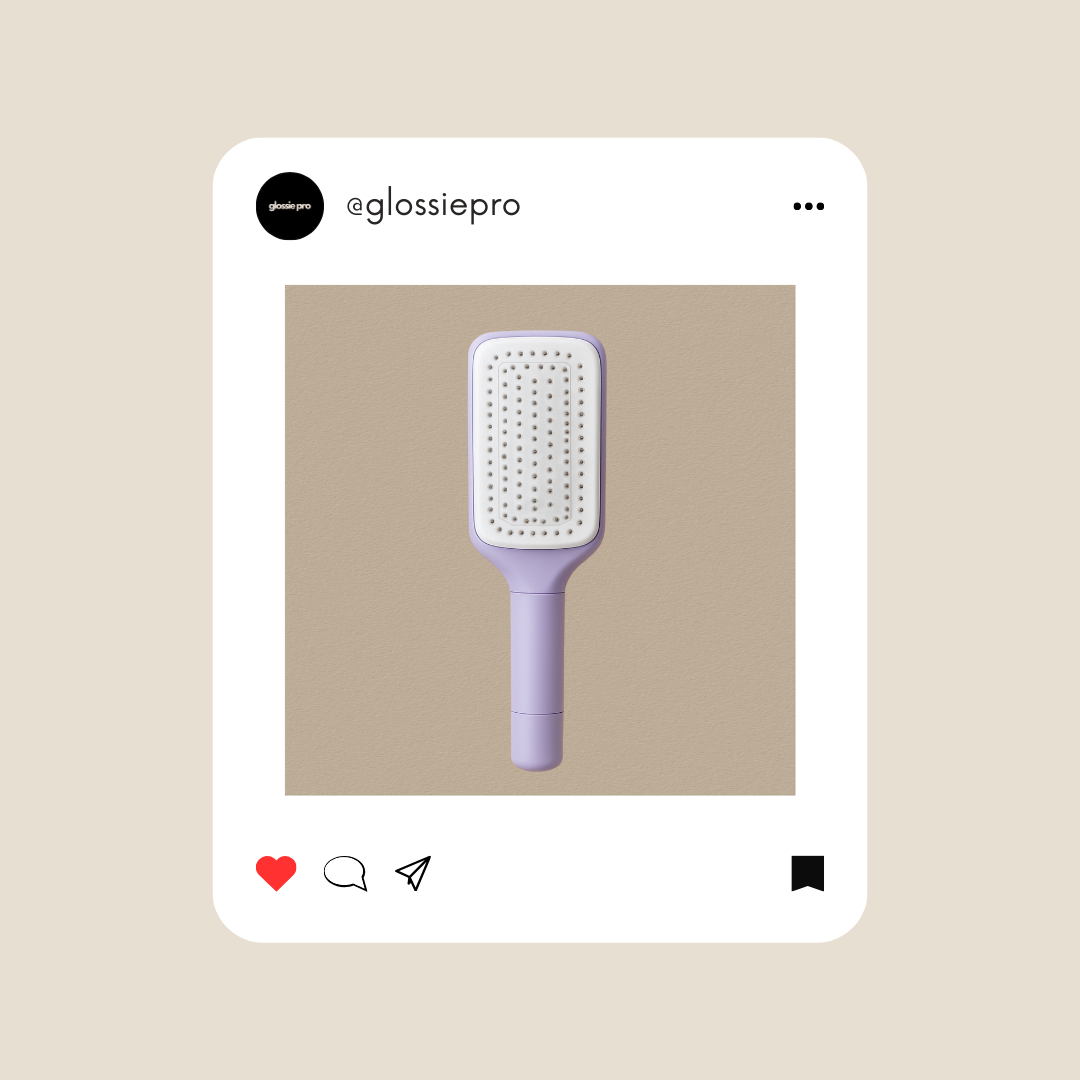 Purple self cleaning paddle hairbrush on a beige background with GlossiePro branding.