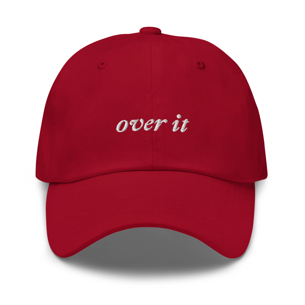 red baseball hat with 'over it' text embroidered in white on a white background