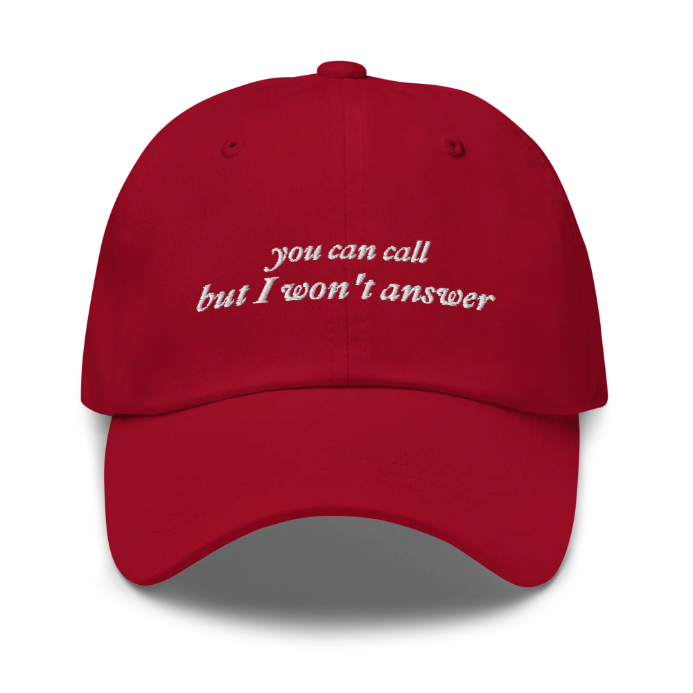 Red baseball hat with white embroidered text 'you can call but I won't answer' on a white background