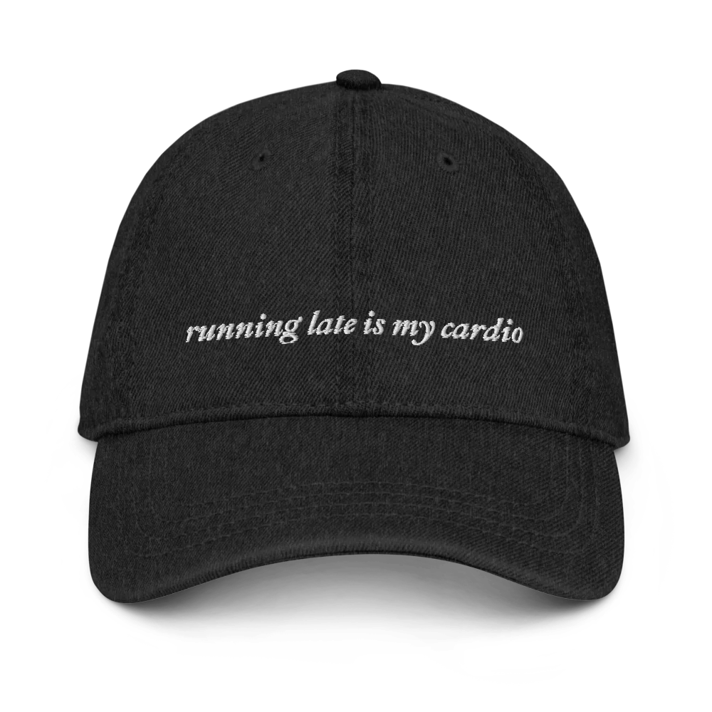 Black denim baseball hat with white embroidered text 'running late is my cardio' on a white background