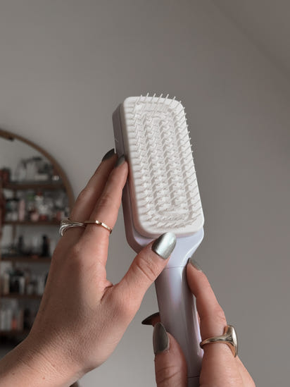 person holding self cleaning hairbrush