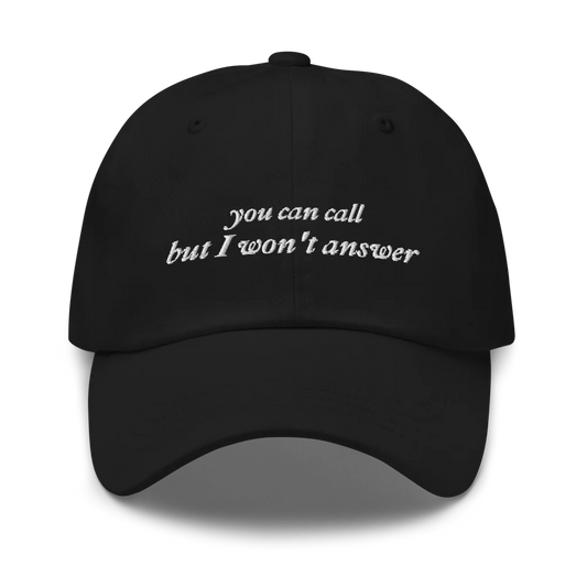 Black baseball hat with white embroidered text 'you can call but I won't answer' on a white background
